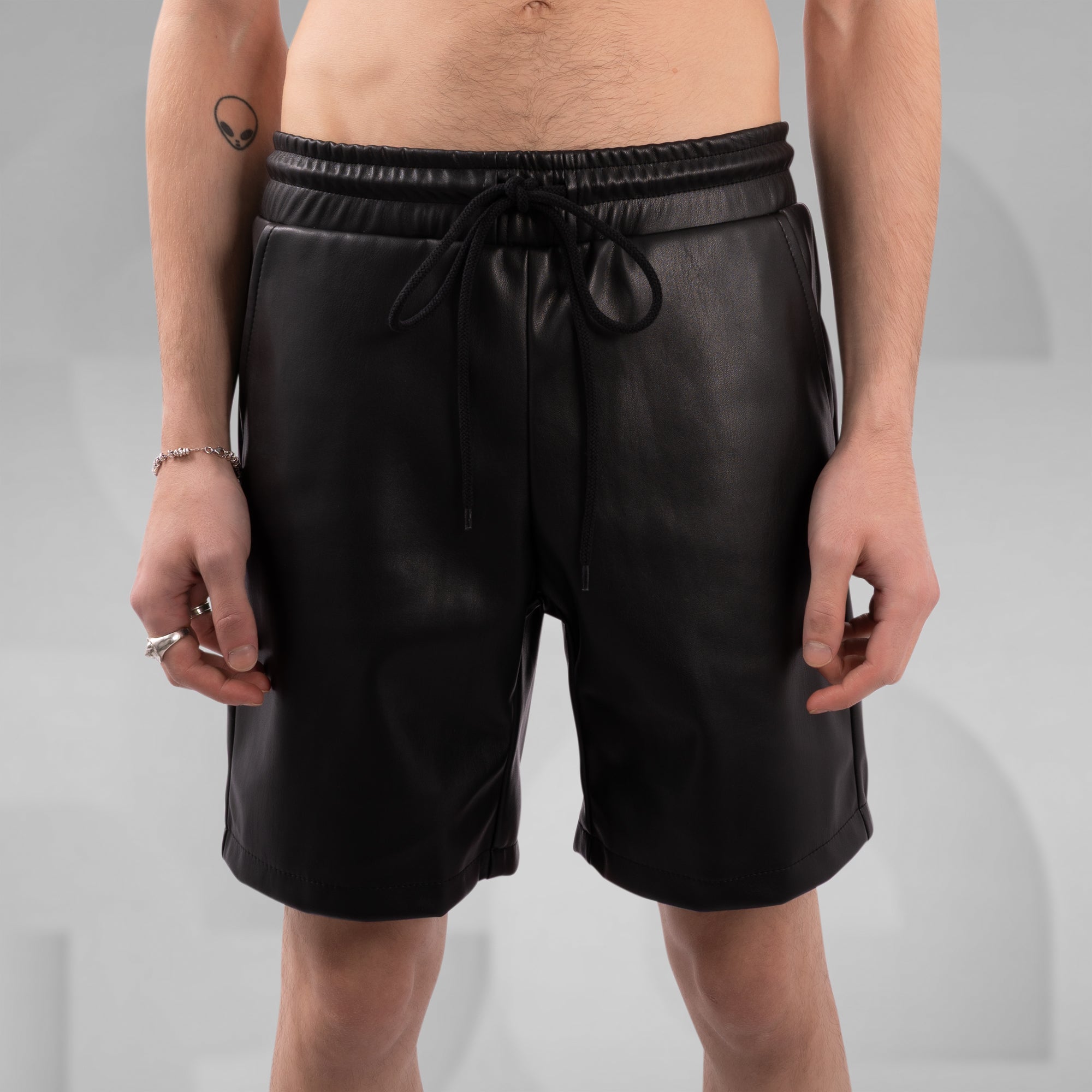 Person wearing black leather shorts on a gray background
