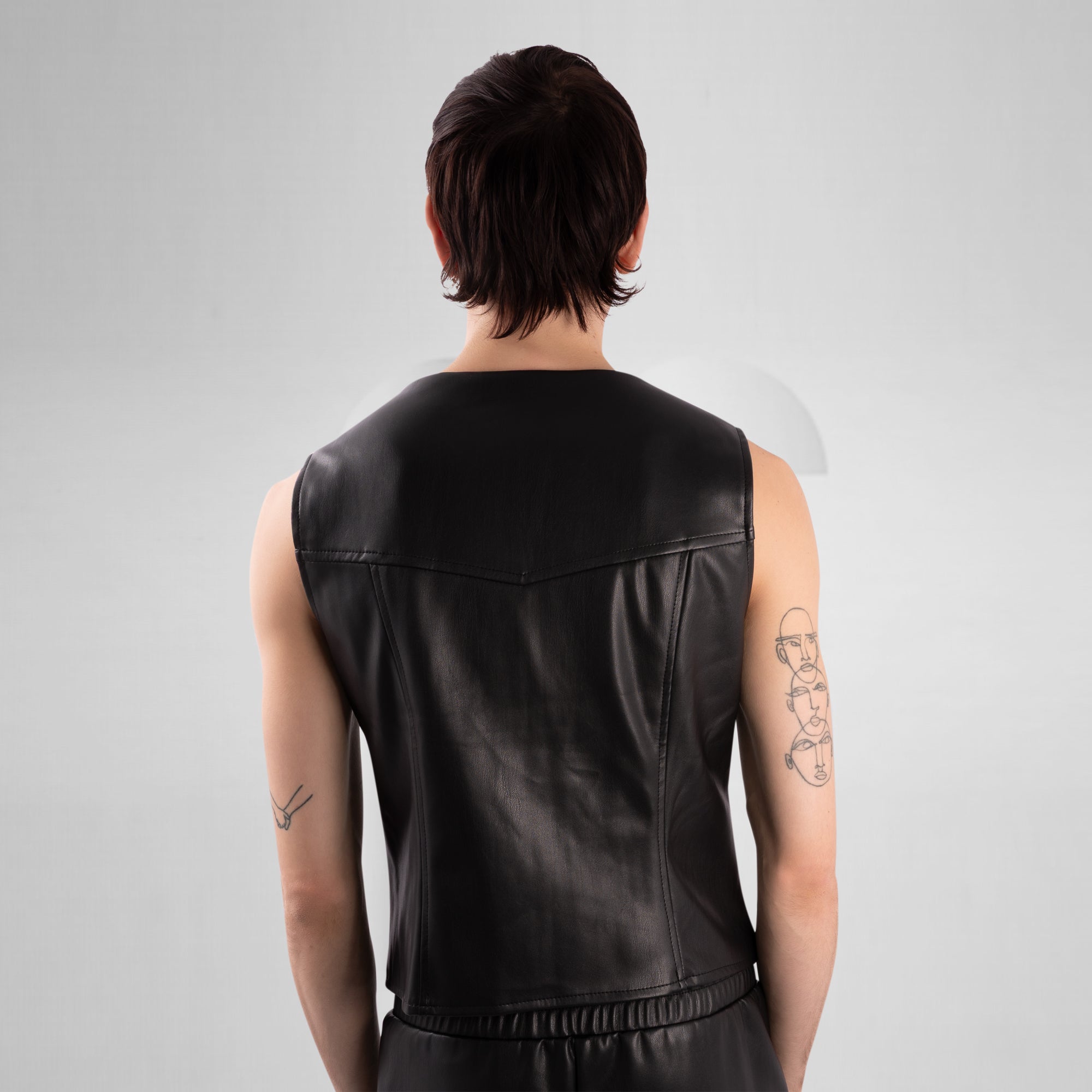 Person wearing a black leather vest on a gray background