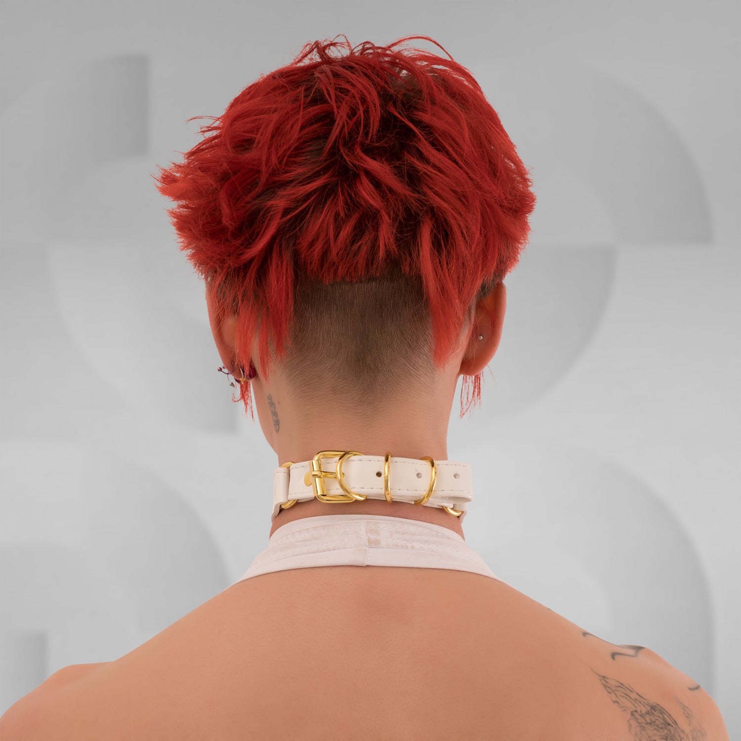 This image features a model showcasing a sleek white PU double choker with striking gold rings at the center front. The choker elegantly frames her neck, adding a bold yet refined touch to her look. Its minimalist design accentuates her features while embodying a modern aesthetic that effortlessly blends sophistication with an edgy vibe.