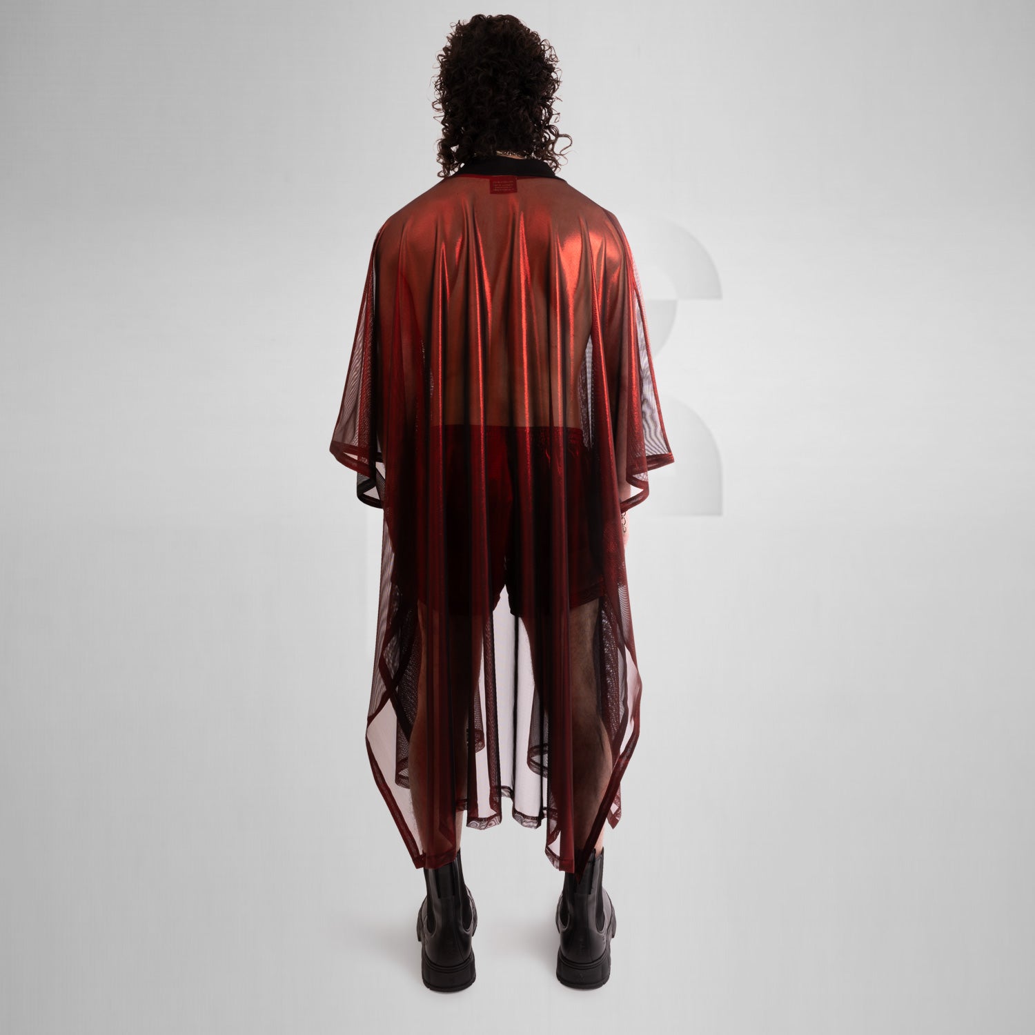 A striking long poncho in red, blue, and silver with a shiny disco festival vibe.