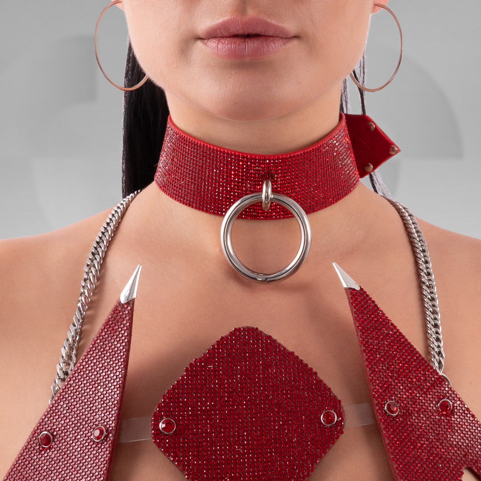 Red beaded choker with a large silver ring and matching top on a neutral background