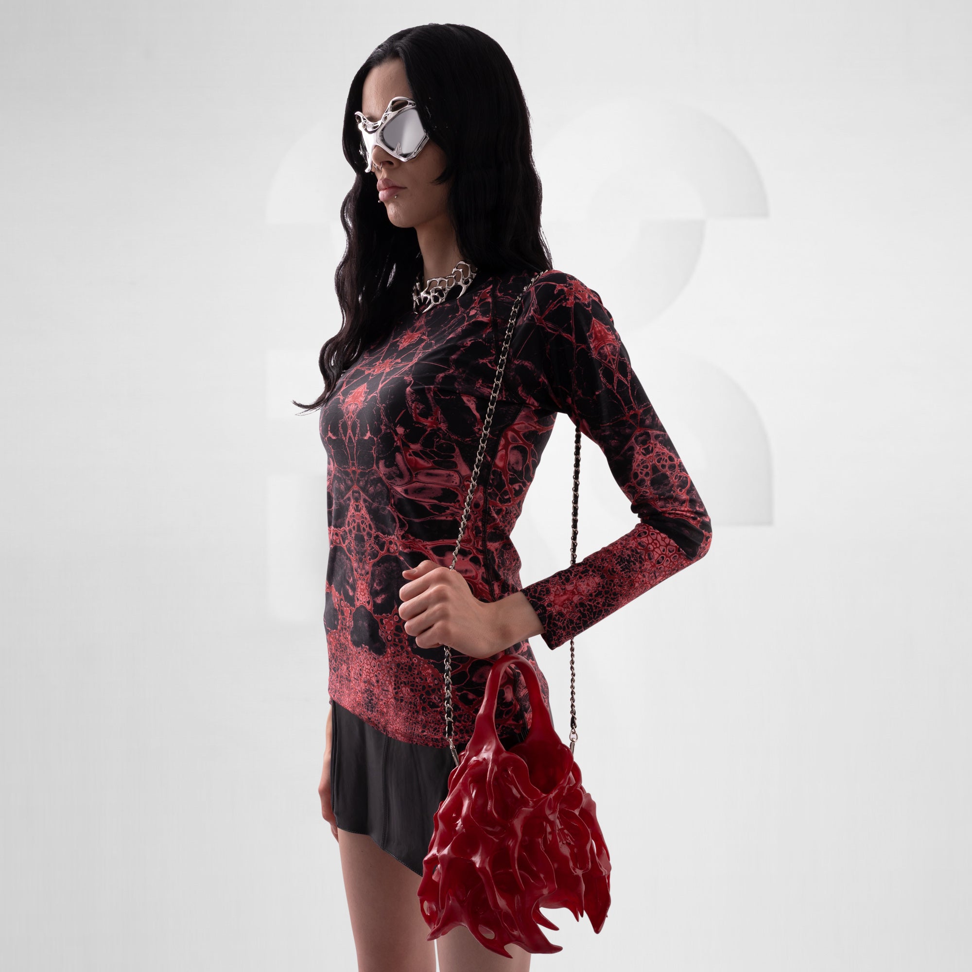Woman wearing a red and black patterned outfit with a matching handbag on a white background