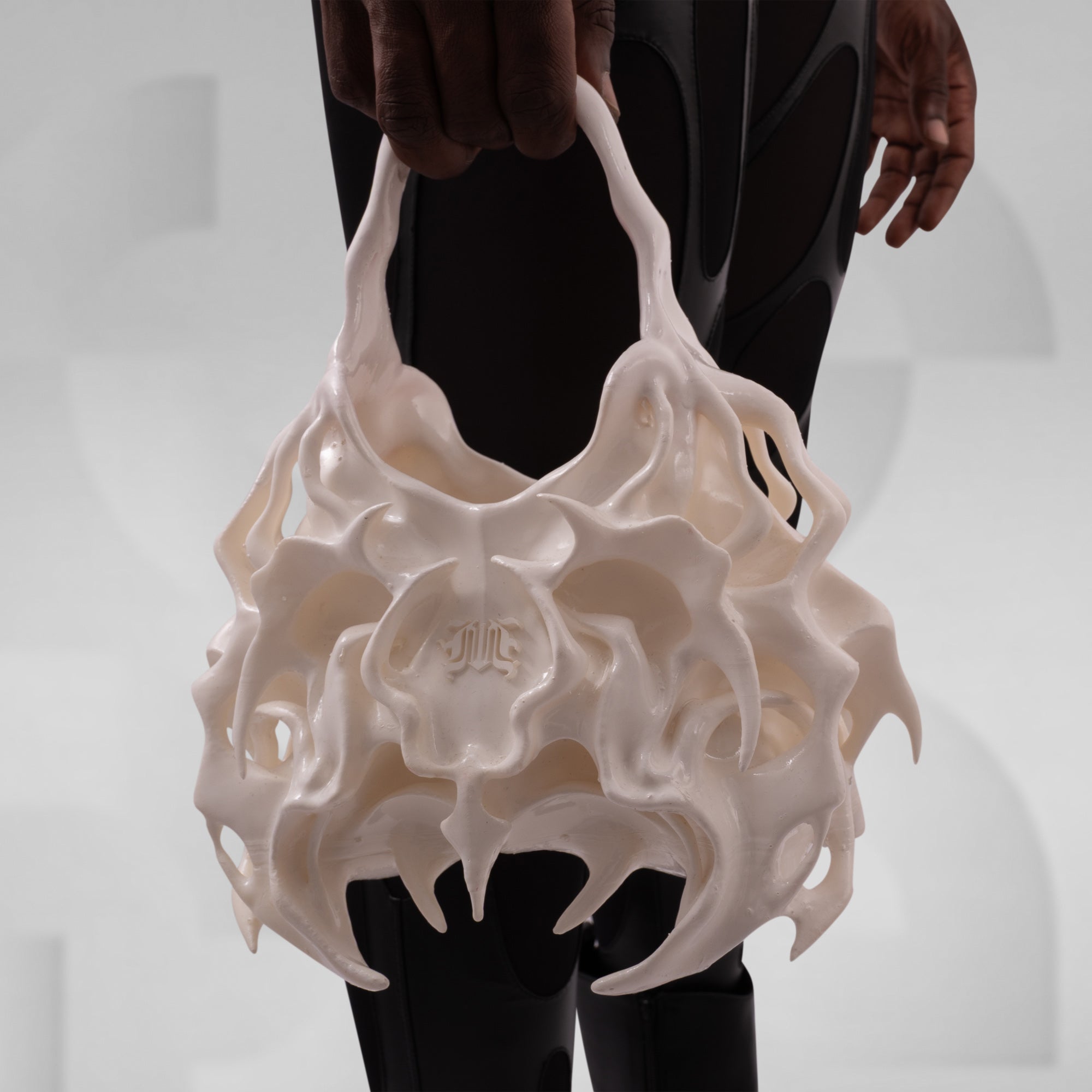 White, intricately designed bag held by a person against a neutral background