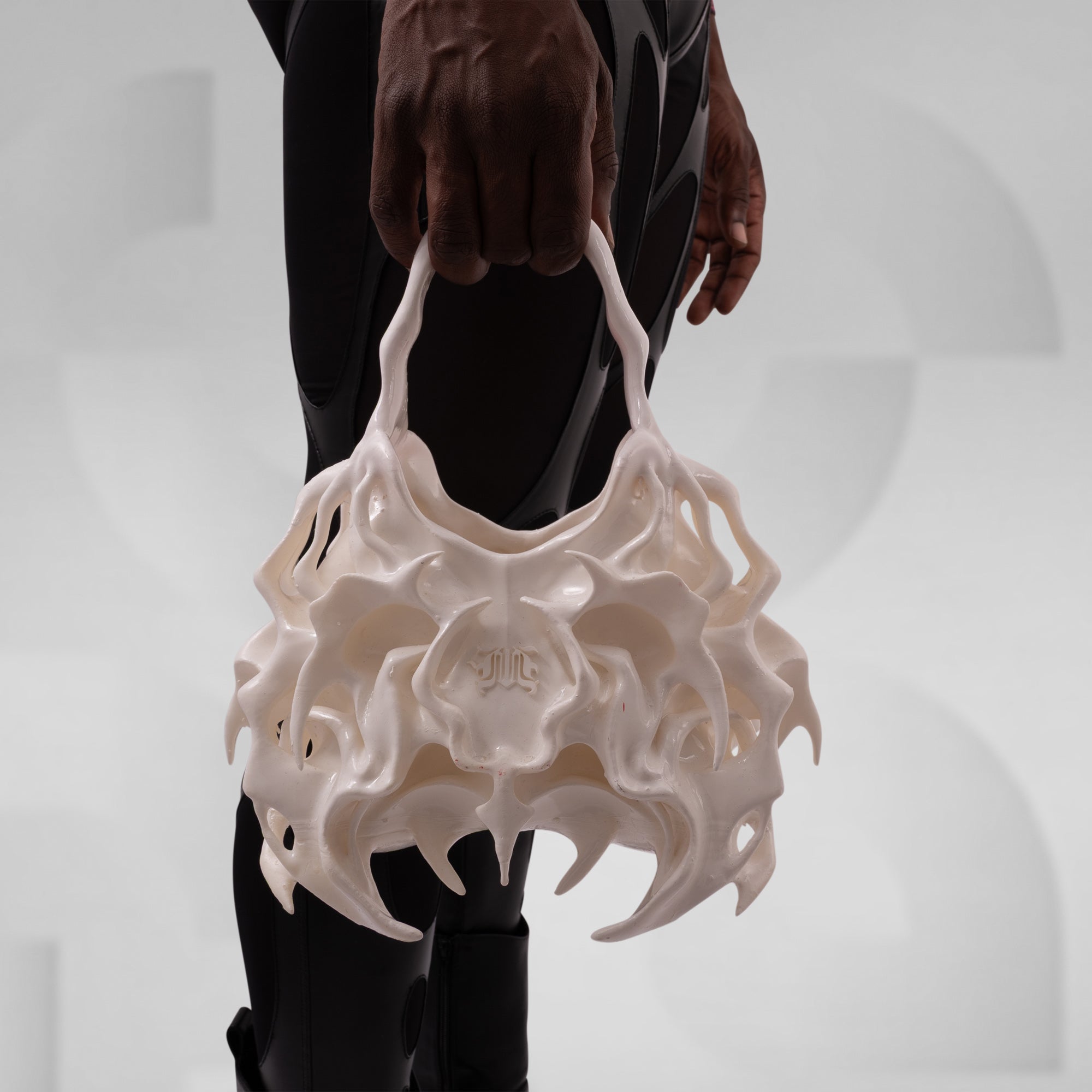 White, futuristic-looking handbag held by a person against a neutral background