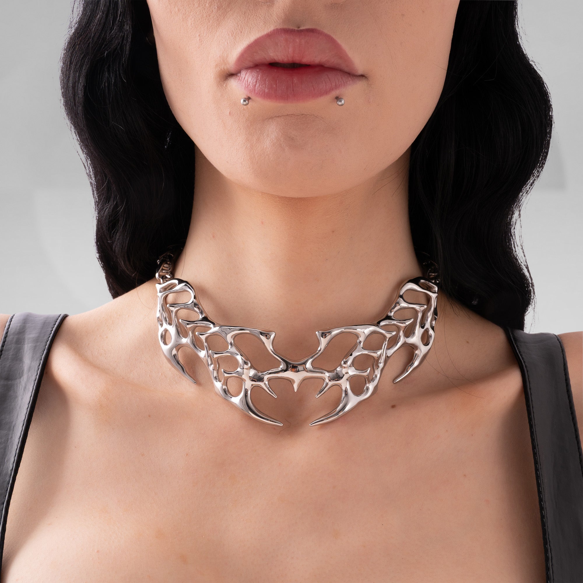 Close-up of a woman wearing a silver necklace with a detailed design.