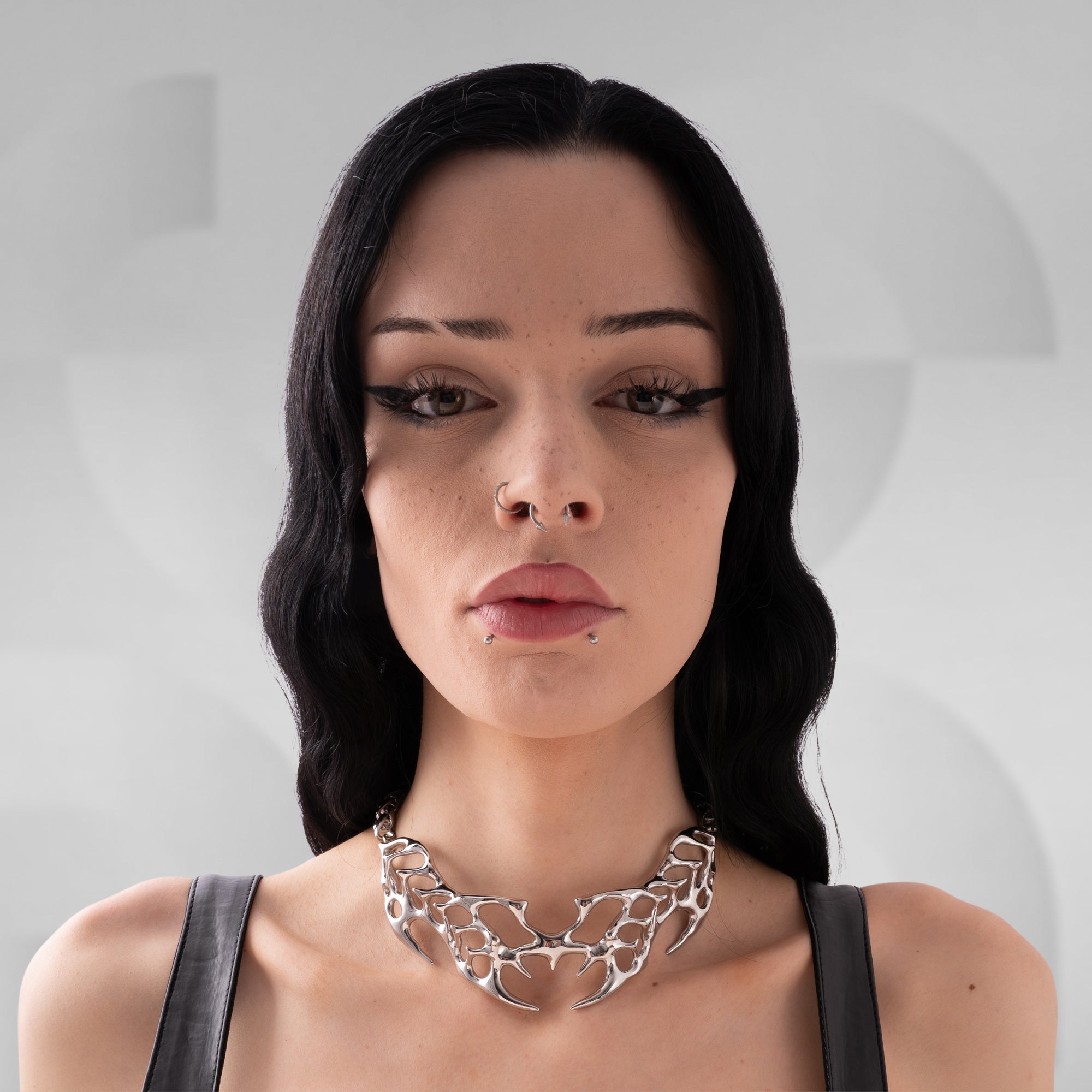 Woman wearing a silver necklace against a neutral background