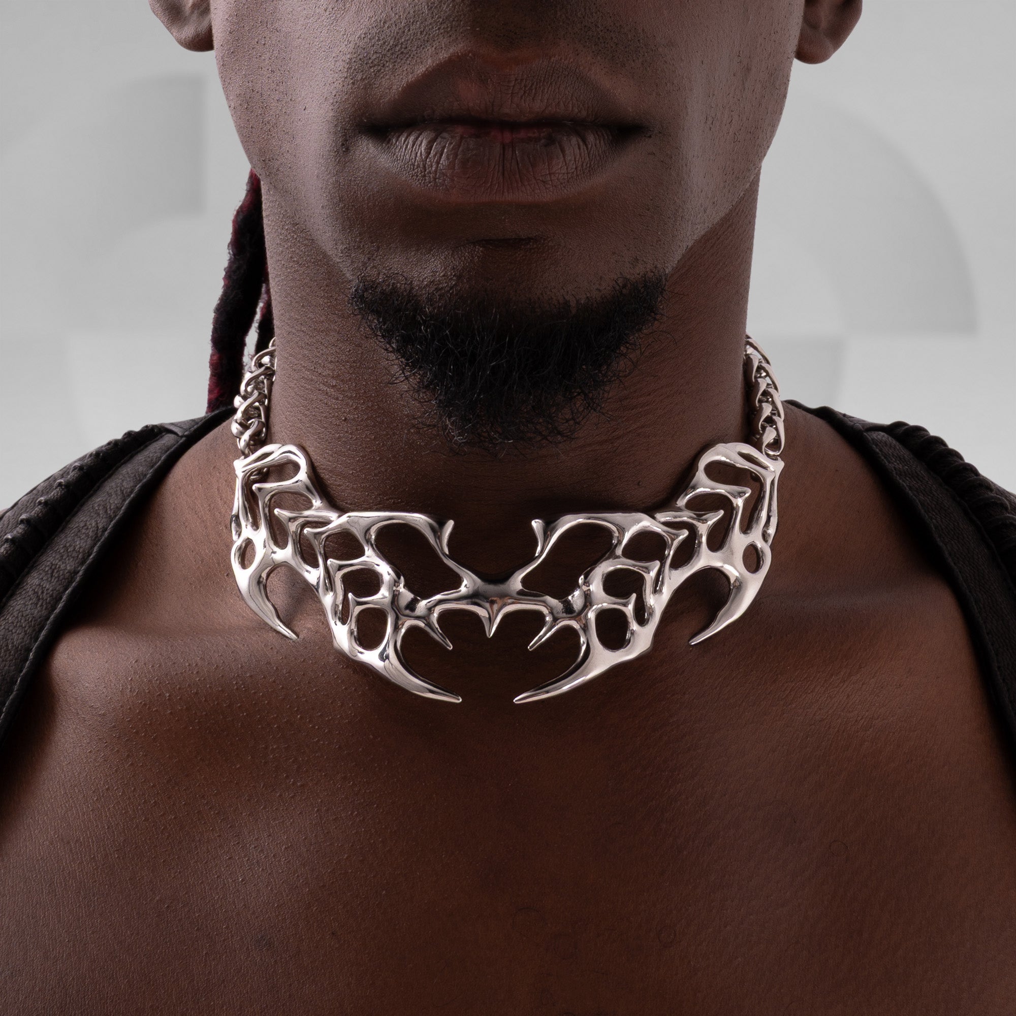 Person wearing a silver tribal-style necklace against a neutral background