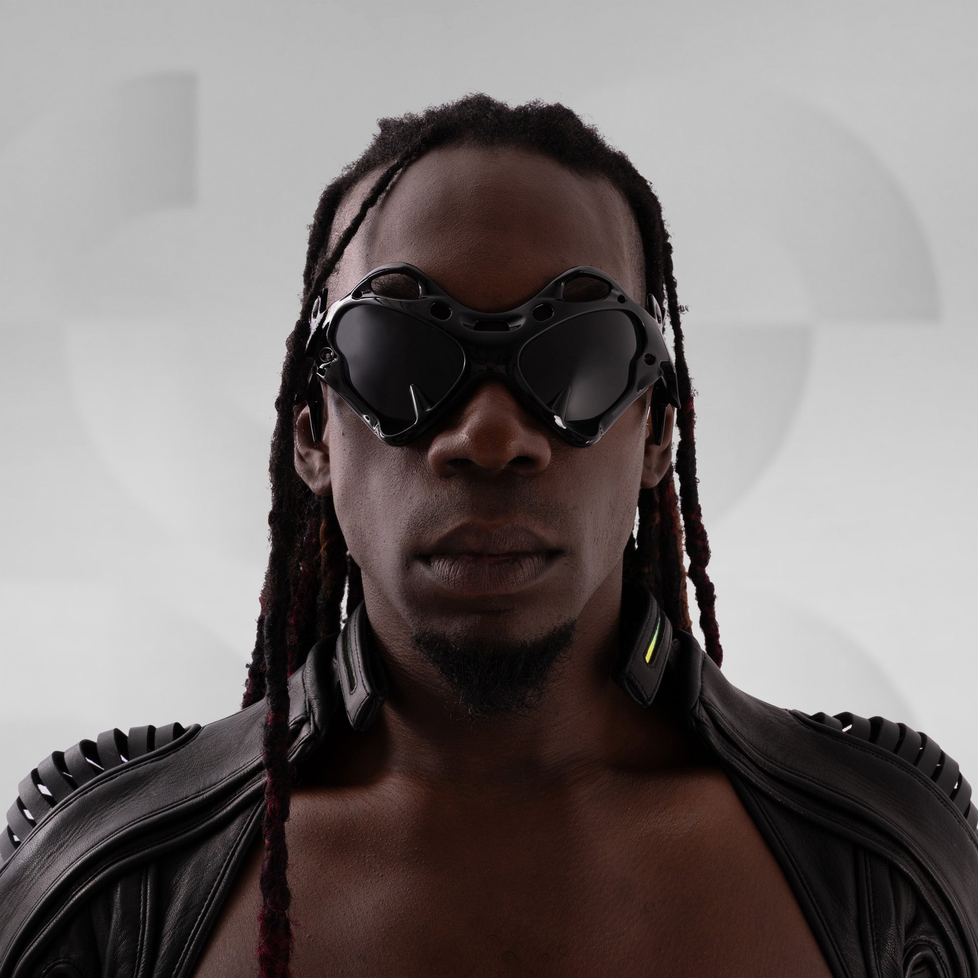 Person wearing futuristic goggles and a black outfit against a gray background