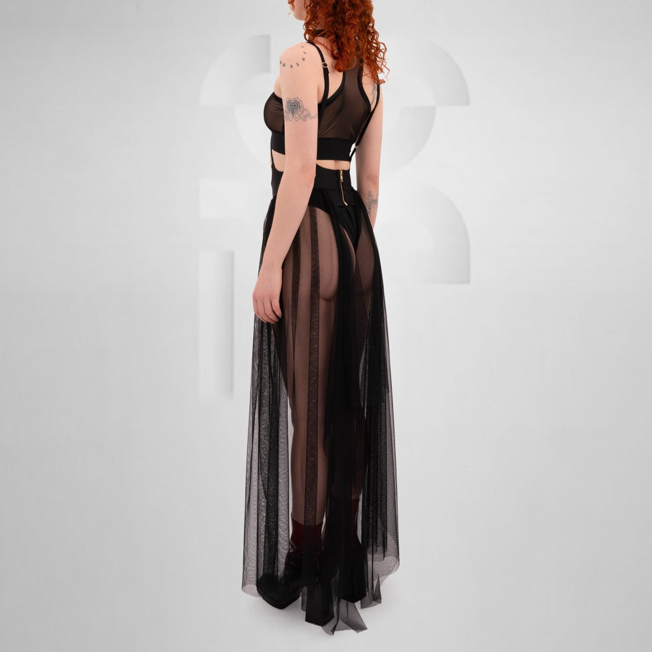 Model wearing a black sheer tulle skirt with thigh-high slits, styled for a Berlin-inspired techno clubwear look.