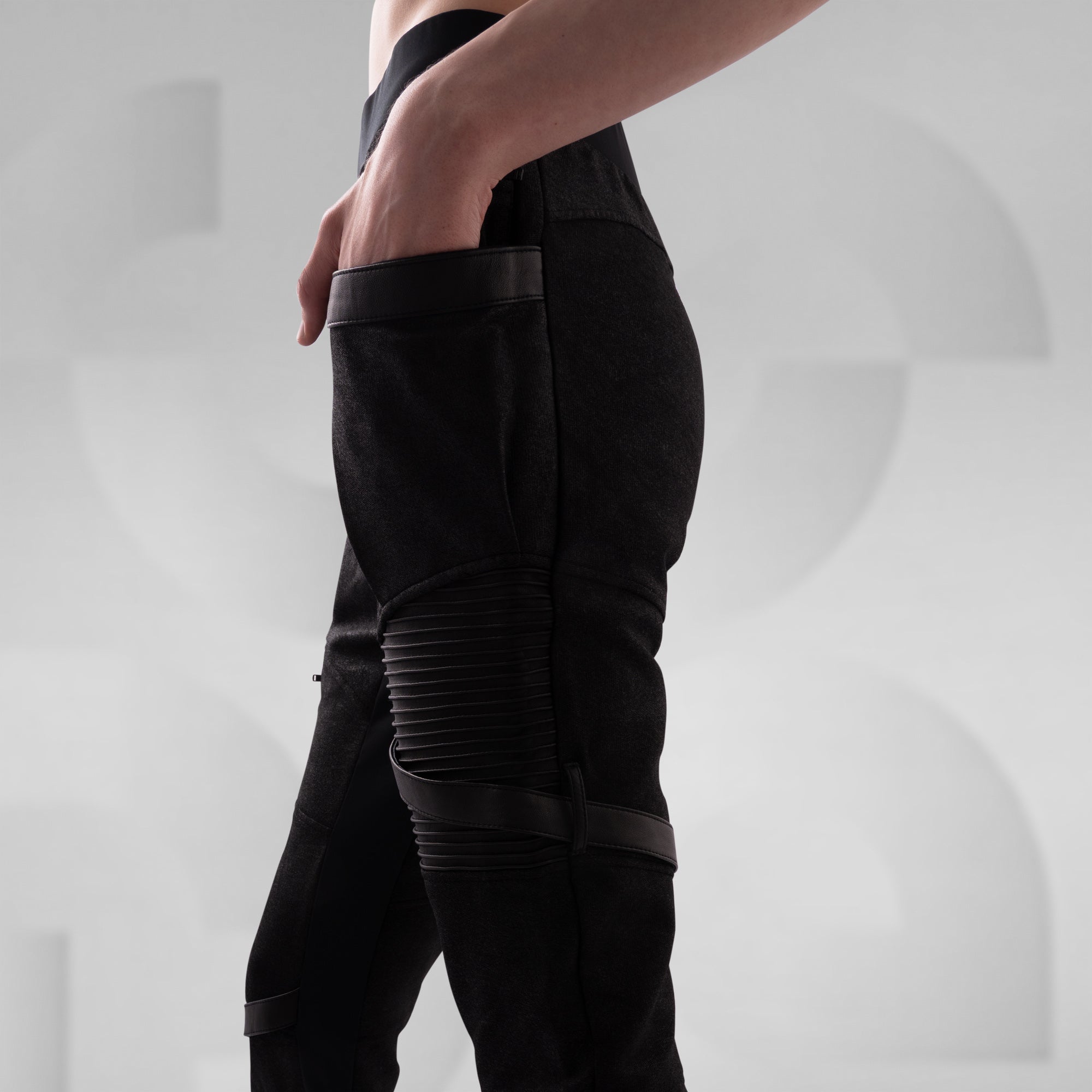 Person wearing black pants with zippers on a light gray background