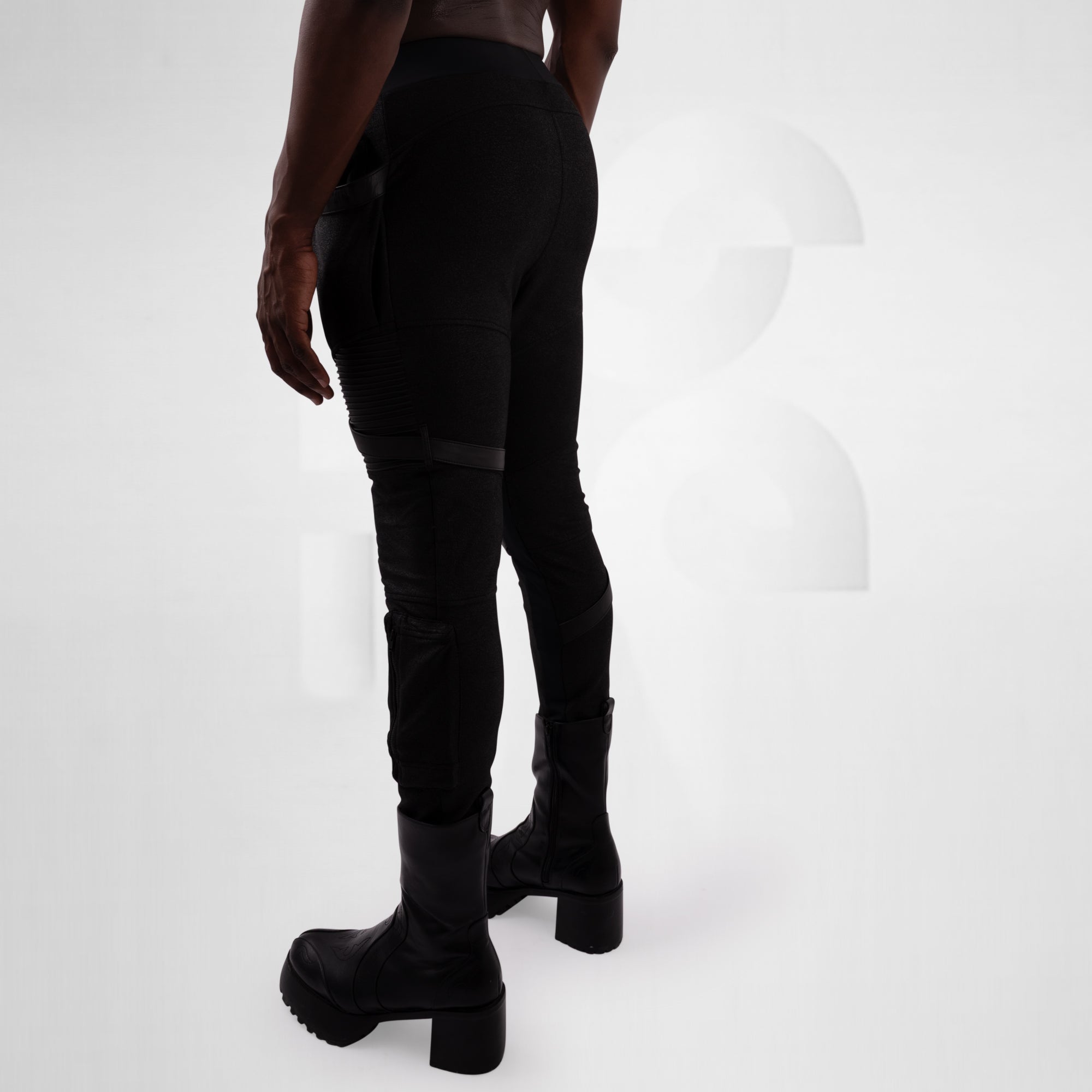 Person wearing black pants and boots on a white background
