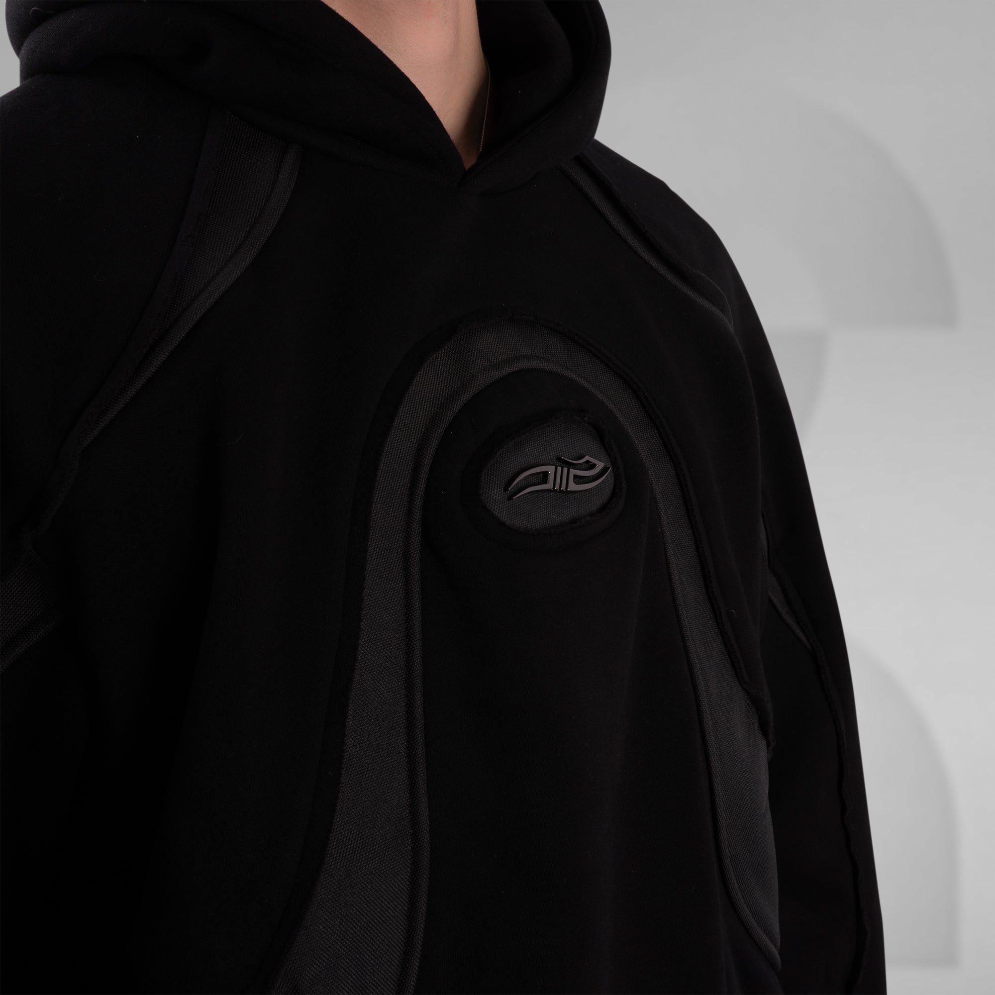 Black hoodie with a logo on the chest against a gray background