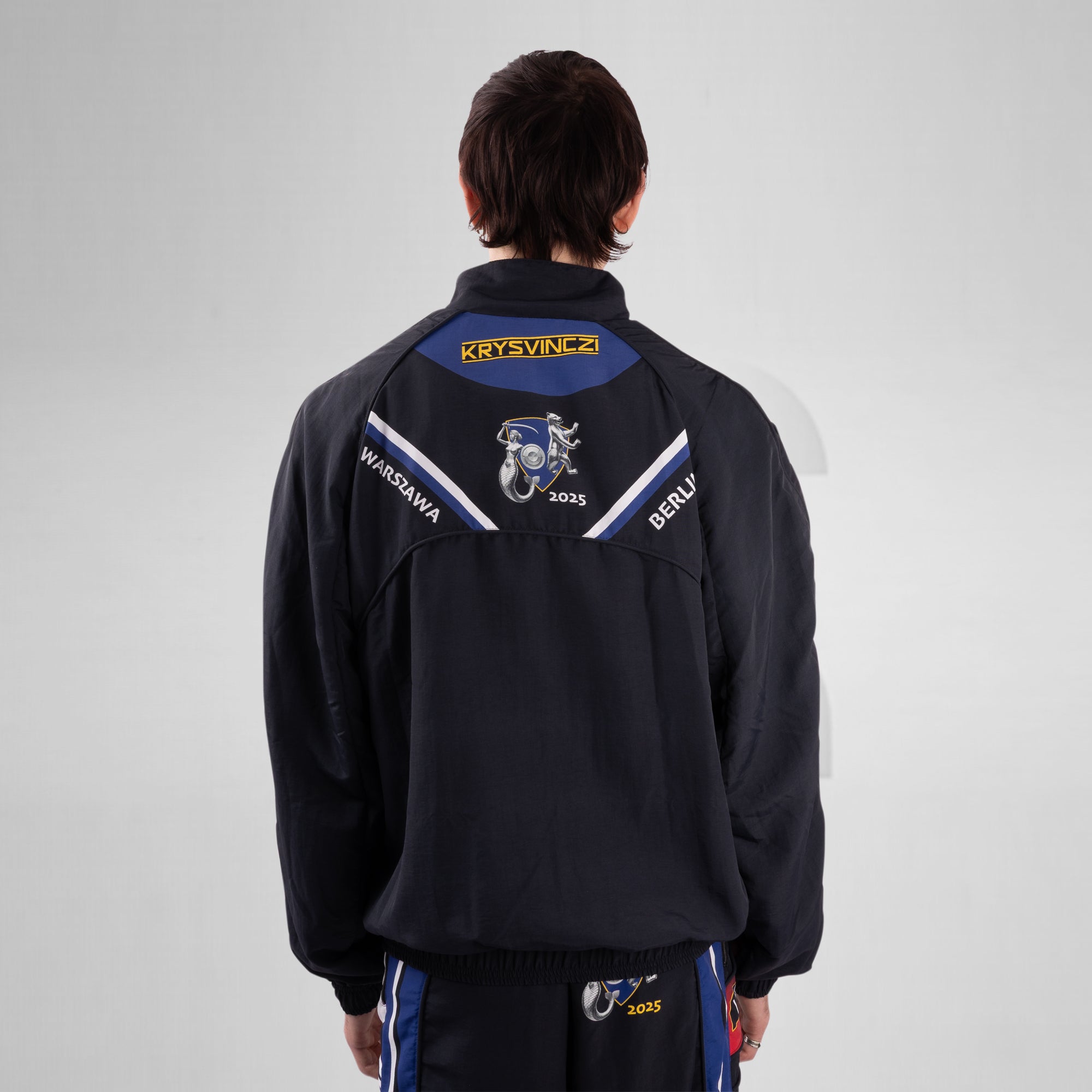 Person wearing a black jacket with branding on the back against a gray background