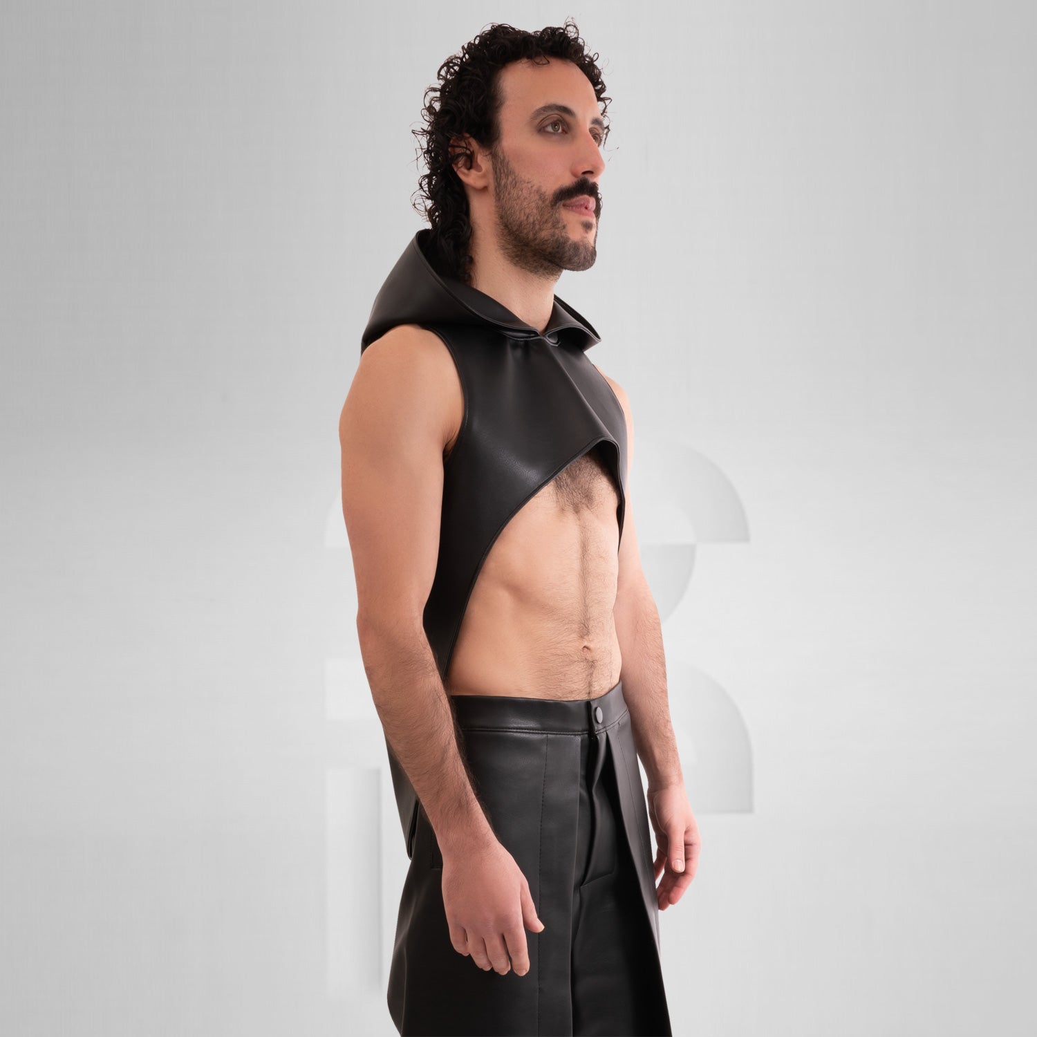 The Vegan Leather Cropped Hoodie by This is Fred features a striking design that combines tribal-inspired elements with a contemporary avant-garde aesthetic. The model showcases this unique piece, which is both bold and eye-catching. Crafted from animal-friendly materials, the hoodie offers comfort and a sense of style that’s perfect for festivals or as an audacious addition to everyday outfits. Its cropped silhouette and distinctive hood create a fashion-forward look that truly makes a statement.