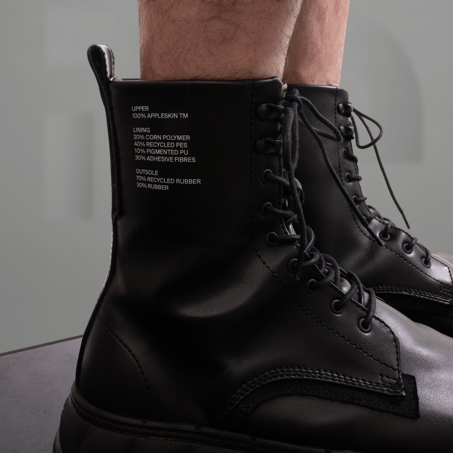 The image showcases a pair of striking black combat boots, featuring a modern twist on classic design. With a chunky sole and sleek leather finish, these boots exude an edgy vibe perfect for the fashion-forward individual. The bold lacing adds a rugged yet stylish touch, making them ideal for both urban adventures and clubwear. An essential addition to any avant-garde wardrobe!