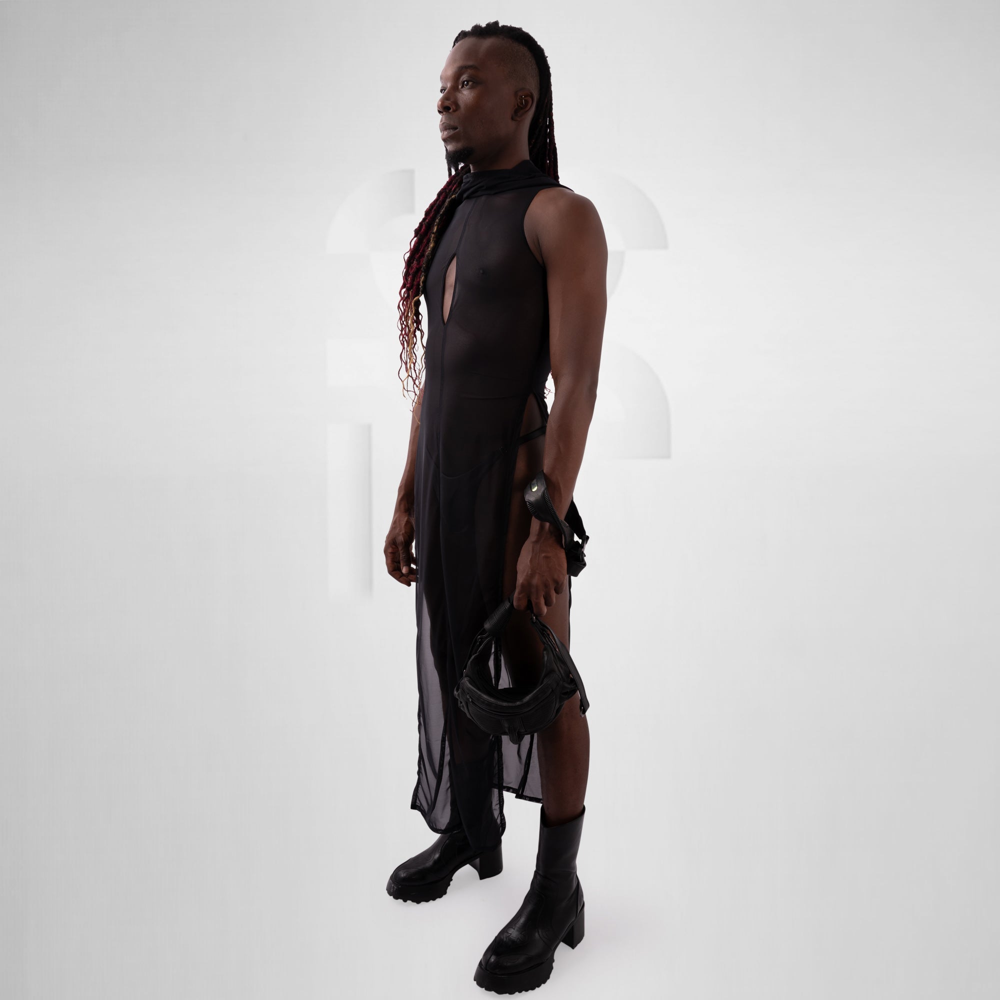 Person wearing a black sleeveless dress with sheer panels on a white background