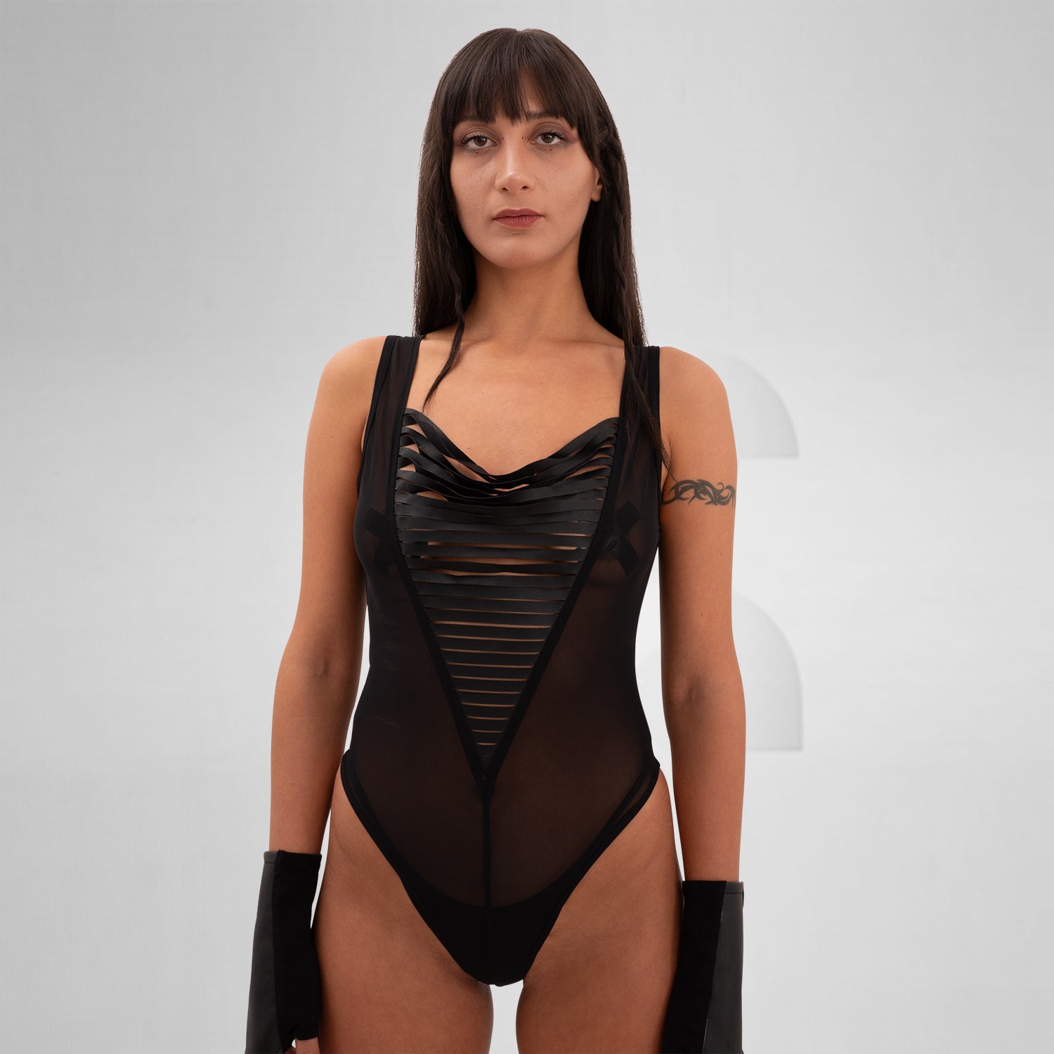 Sheer mesh bodysuit featuring bold vegan leather straps, designed for bold self-expression and dynamic style, perfect for festivals, clubs, and artistic gatherings.