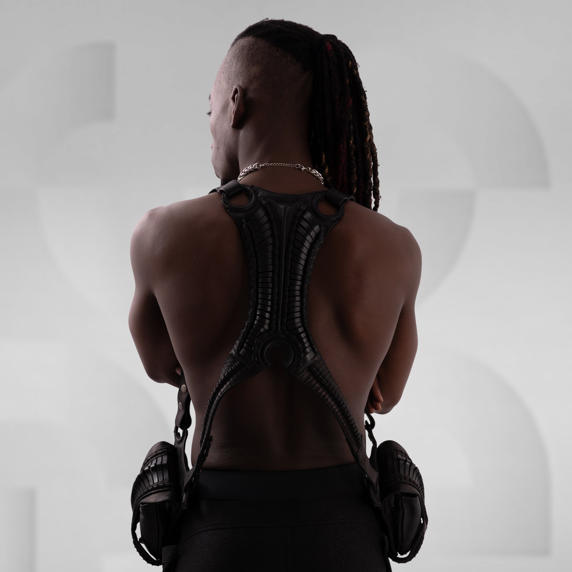 Person wearing a futuristic back piece against a neutral background