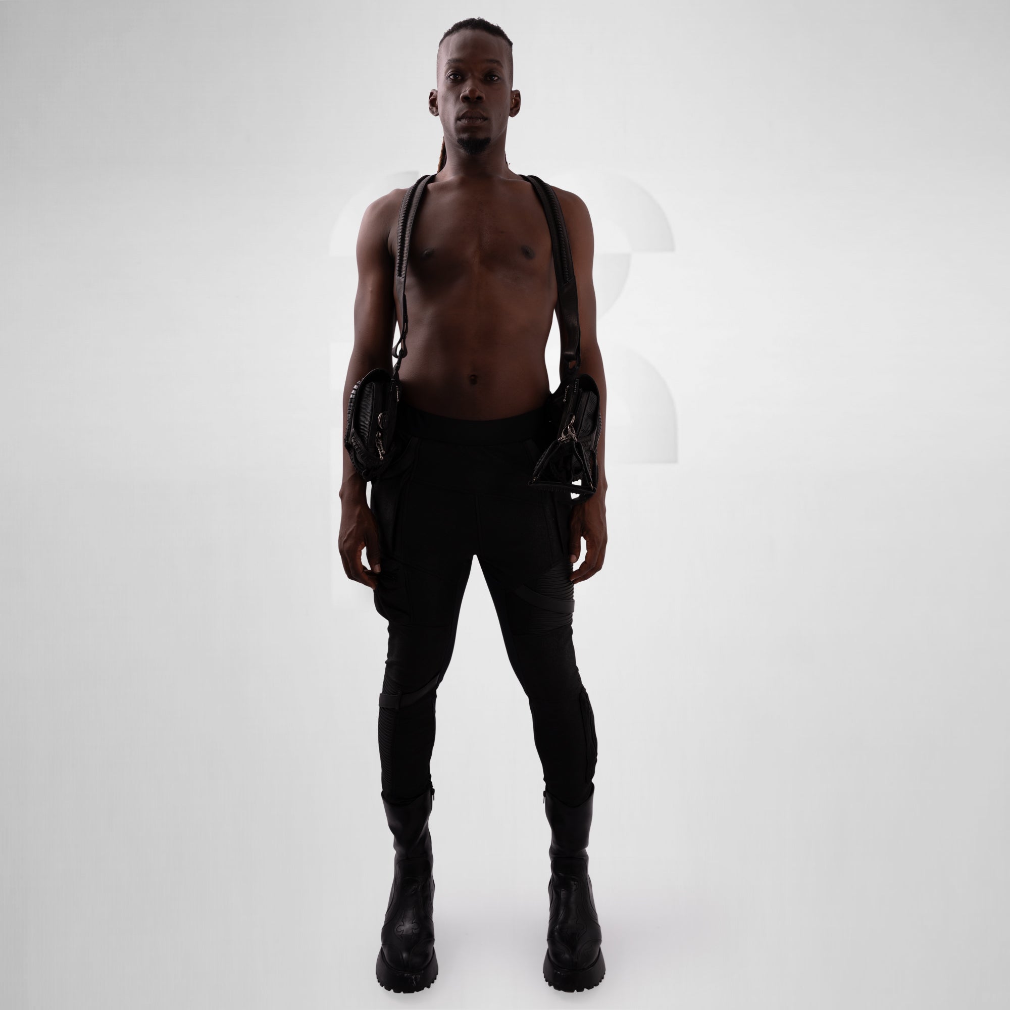 Man wearing black leather suspenders and pants on a white background